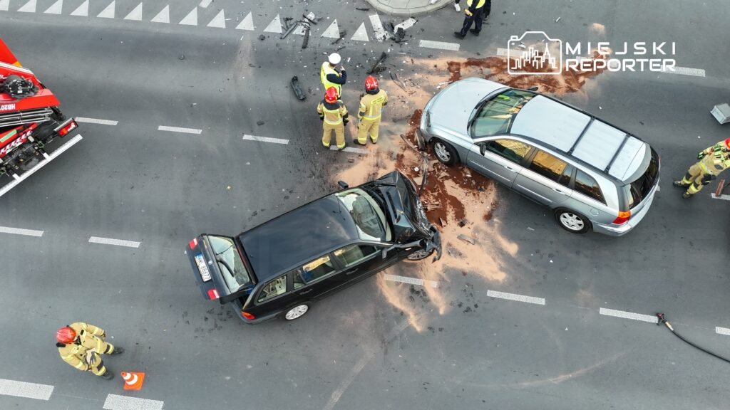 Kierowcy i strażacy badają miejsce wypadku drogowego, gdzie zderzyły się dwa samochody na ulicy.