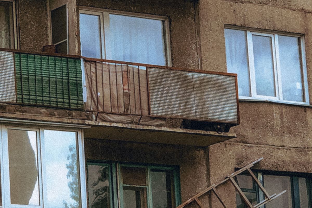 Zaniedbany betonowy balkon w bloku, skorodowana balustrada i zawilgocone czoło płyty balkonowej