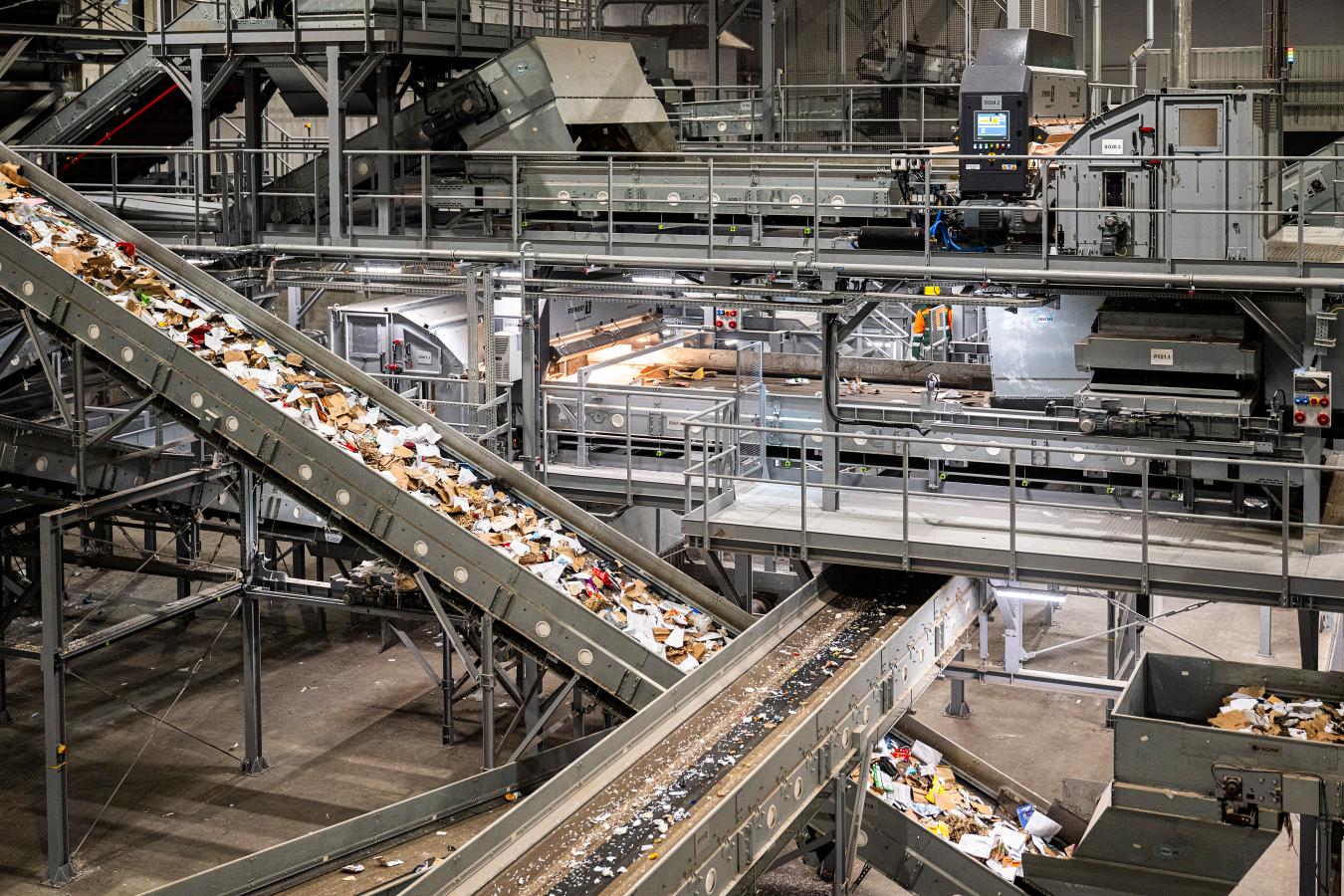 Linia sortownicza w zakładzie przetwarzania odpadów, z przesuwającymi się resztkami materiałów na taśmach.