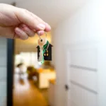 Dłoń trzymająca klucze do mieszkania w drzwiach apartamentu