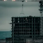 Wieżowiec mieszkalny w budowie z dźwigiem na tle miasta