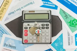 Kalkulator, klucze do mieszkania i dokumenty kredytu hipotecznego na stole